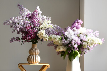 Vase with lilac flowers on shelf in room, closeup