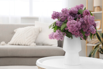 Naklejka premium Vase with lilac flowers on table in living room, closeup