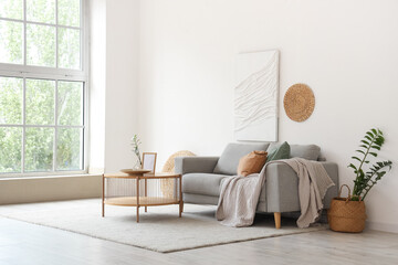 Sofa and wooden coffee table near white wall in interior of living room