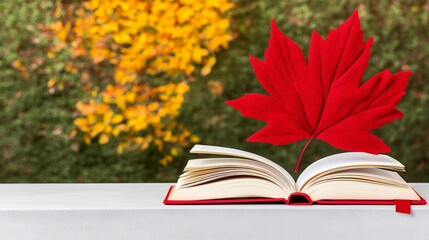 Red Book with Maple Leaf on Autumnal Background