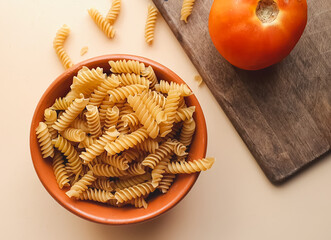 fussilli pasta in a brown ceramic bowl with a light beige background