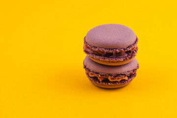 Delicious chocolate macarons on a bright yellow background