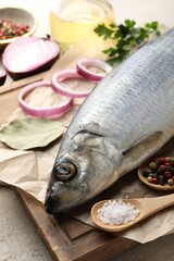 Salted herring and spices on light grey table, closeup