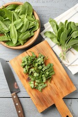 Cut fresh sorrel leaves and knife on grey wooden table, flat lay