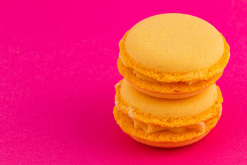 Bright yellow macarons arranged on vibrant pink background