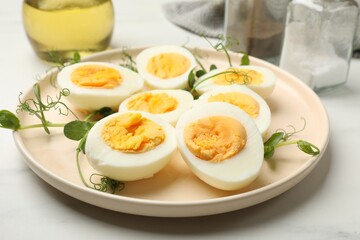 Boiled eggs and microgreens on white marble table, closeup