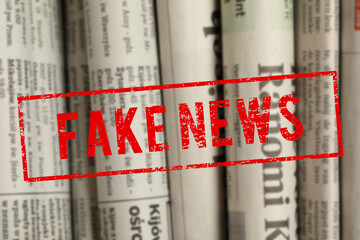 Red Fake News stamp and newspapers in different languages as background, closeup