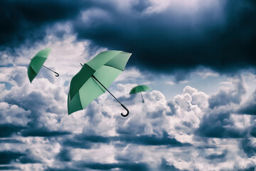 Green umbrellas flying in cloudy sky. Stormy weather