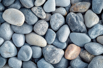 Natural smooth gray pebbles and round stones forming an abstract textured pattern background