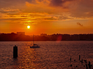 Orange sunset over water and a sailboat in New York © Robert Arango L