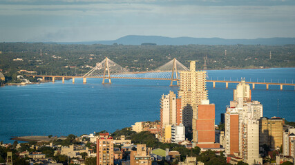 Cityscape of Posadas, Argentina, with the San Roque González de Santa Cruz Bridge spanning the Paraná River in the background.