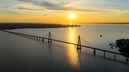 Breathtaking aerial view of the San Roque González de Santa Cruz Bridge at sunset, with the city of Posadas in the background.