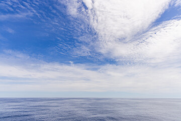 Bright Blue Sky and Cloudscape Over Calm Pacific Ocean Horizon