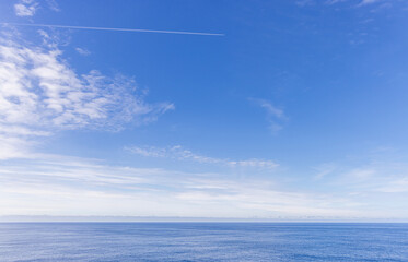 Serene Ocean Panorama with a Contrail in a Vibrant Blue Sky