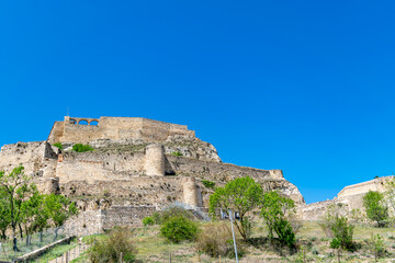 Fototapeta premium Medieval fortress on hilltop surrounded by green vegtation Spain