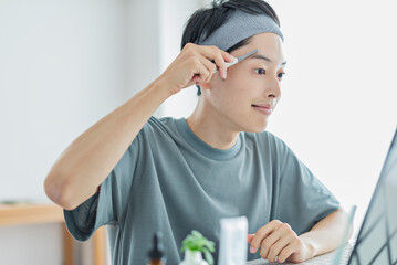 シェーバーで眉を整える若い男性
