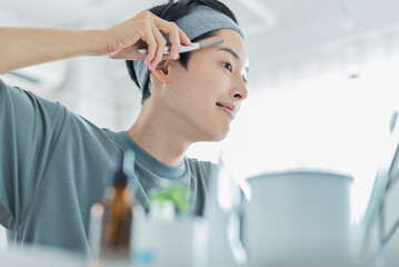 Naklejka premium シェーバーで眉を整える若い男性