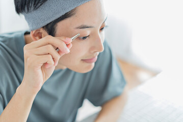 毛抜きで眉を整える若い男性