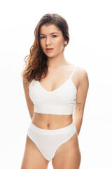 Obraz premium Young fashion female model with long curly hair wearing white lingerie posing in studio over white background