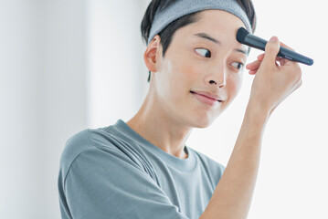 ブラシでファンデーションを塗る若い男性