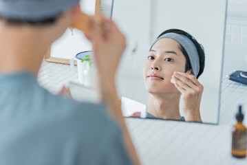 スポンジでファンデーションを塗る若い男性