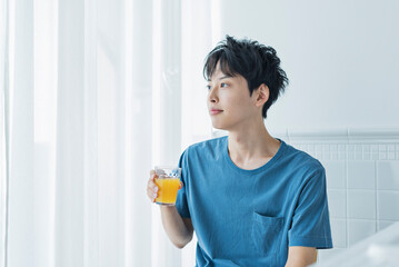 朝にオレンジジュースを飲む若い男性