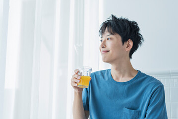 朝にオレンジジュースを飲む若い男性
