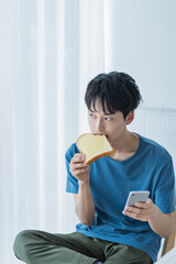 朝食を食べながらスマートフォンを見る若い男性