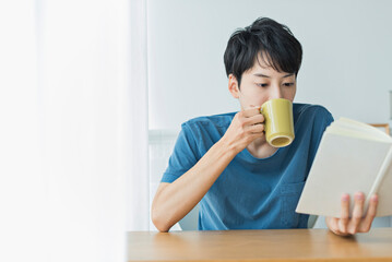 コーヒーを飲みながら本を読む若い男性