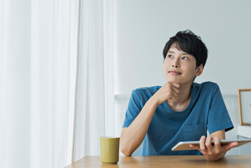 Naklejka premium 休日にタブレット端末で動画を見る若い男性
