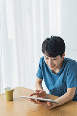 休日にタブレット端末で動画を見る若い男性