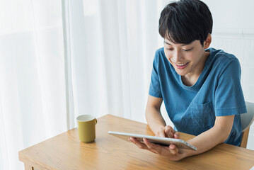 休日にタブレット端末で動画を見る若い男性