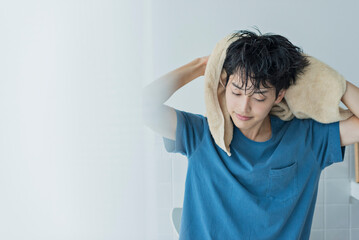 風呂上がりにタオルで髪を乾かす若い男性