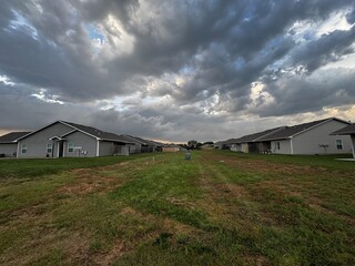 Storm clouds loom over the rooftops of cookie cutter suburban duplexes - representing the potential...