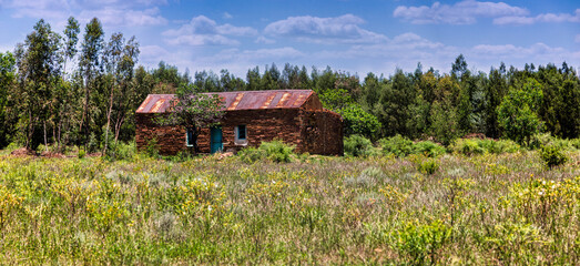 homestead ruins, stone rock house with corrugated sheet rusted roof, south african vintage architecture, old farm house in the wilderness
