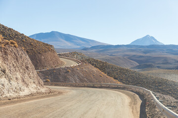 Curved dirt road winds through the high-altitude desert near the Licancabur Volcano in northern Chile. A scenic and remote Andean landscape. Ideal for travel, nature, and editorial use.
