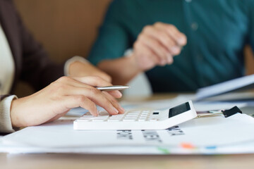 Finance and Calculation. A professional using a calculator for financial analysis in a business meeting.