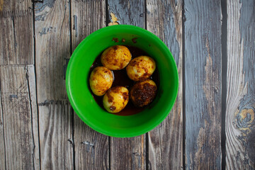 Savory eggs coated in spicy sambal sauce, ready to enjoy in a vibrant green bowl.