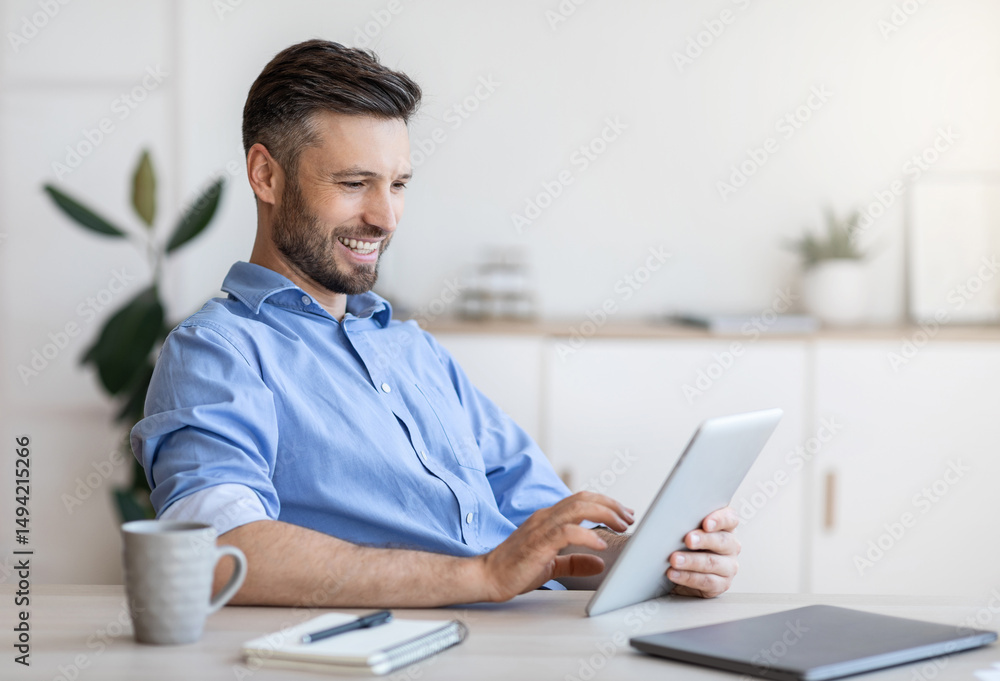 Poster handsome young businessman using digital tablet at workplace in office, browsing new application or 