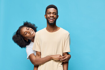 Obraz premium Happy young couple embracing each other against a bright blue background, showcasing love and joy with vibrant clothing and cheerful expressions