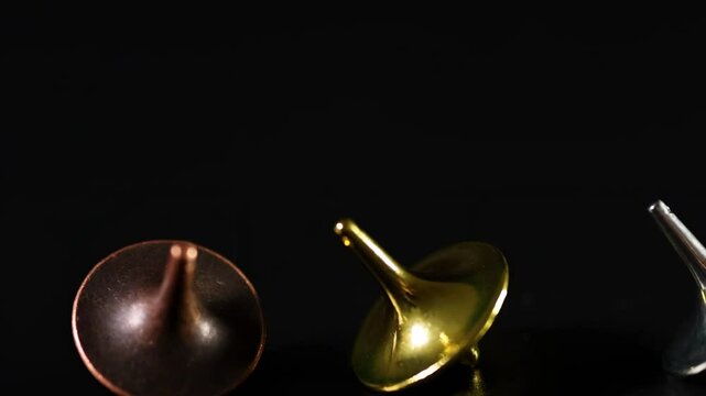 Metallic Tops Spinning on Dark Surface