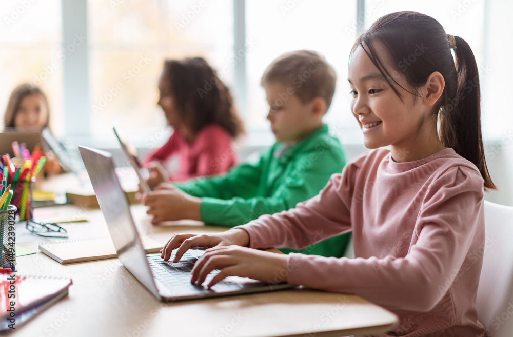 Aufkleber online learning. diverse children using laptop in modern classroom at school, selective focus on hap