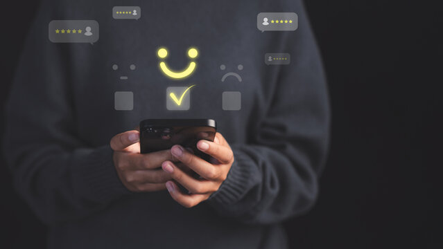 Female customer using a smartphone select a happy face icon on digital feedback. Concept of customer satisfaction, testimonial, online reviews, user feedback, review rankings and service quality.