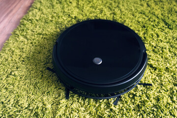 cleaning fleecy carpet with an automatic vacuum cleaner. Robot vacuum cleaner on floor, Smart robotic automate wireless cleaning technology machine in living room. top view