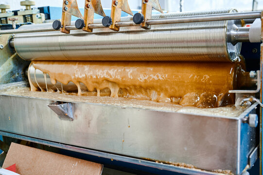 Innovative glue-spreading machine in action with swirling hot glue creating a seamless application process during a manufacturing operation