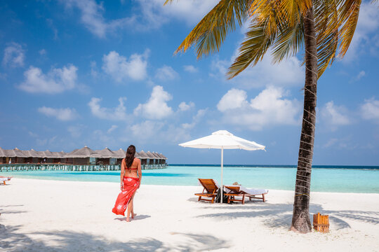 Woman standing near palm tree on a beach in the Maldives
