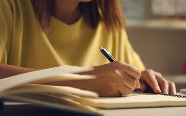 Asian woman works from home, surrounded by notes, a laptop, and messages. She browses the internet, writes ideas, and researches for her startup, utilizing wireless technology.