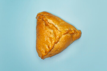 kulebyak or khachapuri. triangular pie with filling on a blue table. Traditional pastries of Central Asia, Russia. bright blue background color.