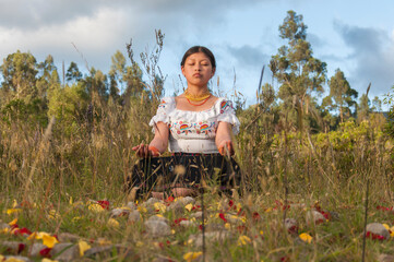 Young latin american woman meditating outdoors in nature with flower petals and stones