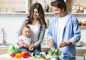 Vegan family. Parents with baby cooking organic healthy lunch at kitchen